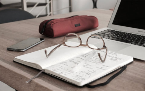 table with laptop, book, and glasses