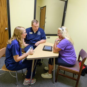 a student and professor consult with an adult in an observed setting within the Mary K Chapman center
