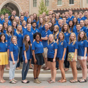 University Ambassadors standing all together in their blue tour shirts on a sunny day on campus