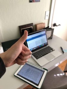 Julianne Tran giving a thumbs-up sign in front of her laptop computer and new study space