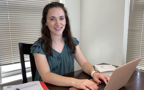 Speech-language pathology master's student Gabrielle Cozart sitting at a table with a laptop computer