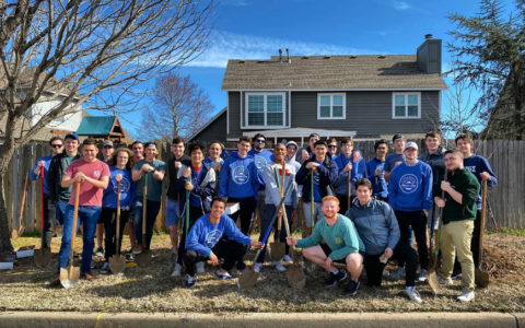 A large group of Kappa Sigma fraternity members standing outdoors holding shovels