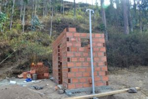 A small, roofless red-brick building during construction