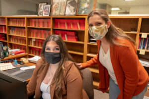 two women in an office while wearing face masks