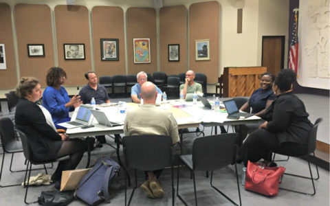 a group of eight people seated around a meeting table