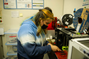 young woman handling material near a 3D printing machine