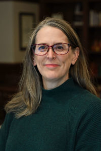 woman with long blonde hair wearing glasses and a green top