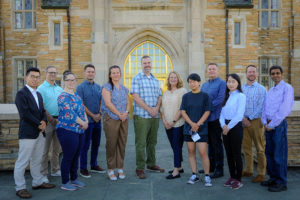 Group of people standing outside an arching doorway posing for a photo