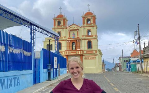 woman in nursing scrubs on a cobblestone road smiling for a picture