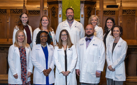 Group smiling wearing white coats