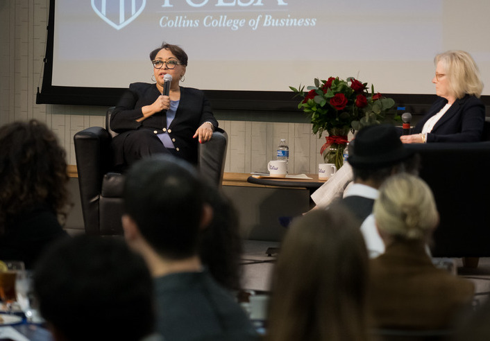 speaker sitting in chair and talking to crowd at friends of finance lecture