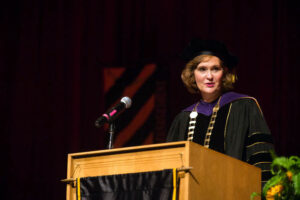 woman standing behind a podium while wearing academic robes