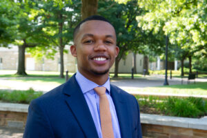 law student in a suit smiling for the camera outside
