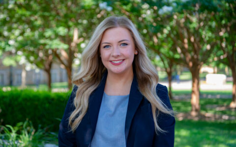 woman with long blonde hair standing outdoors while wearing a blue blazer