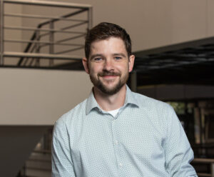 Photo of Andrew Morin wearing light blue shirt inside of Keplinger Hall