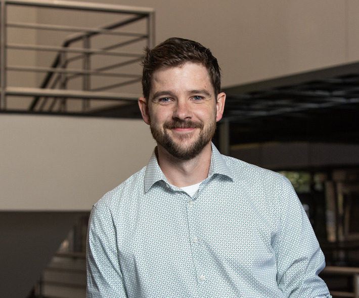 Photo of Andrew Morin wearing light blue shirt inside of Keplinger Hall