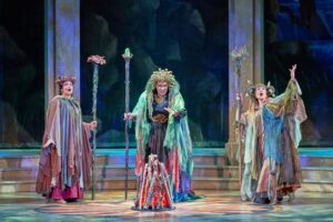 three colorfully dressed women in costume on stage during the opera Dido and Aeneas