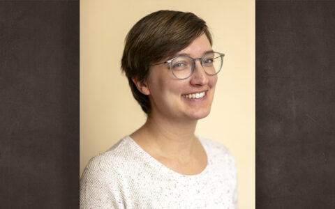 woman with short hair, glasses and a white top smiling