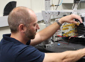 man in a blue polo shirt handling scientific instruments