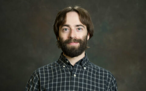 man with long hair and beard in a checked shirt