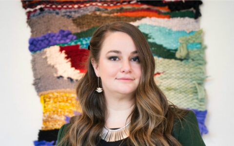 woman with long hair standing in front of a colorful artistic background