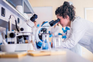 woman looking through a microscope in a laboratory