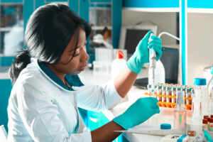 young woman with dark hair wearing a white lab coat and handling medical samples and test tubes