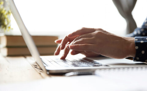 a woman's hands typing on a laptop computer