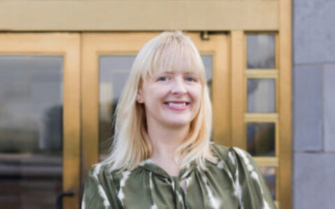 Jennifer Croft, creative writing faculty, smiles in front of building.