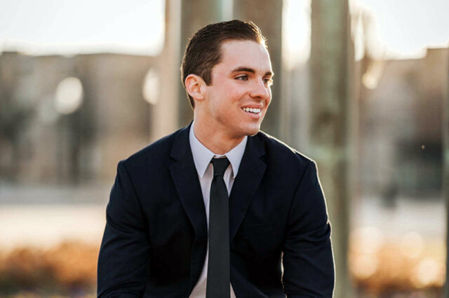 Photograph of a smiling young man in a black suit