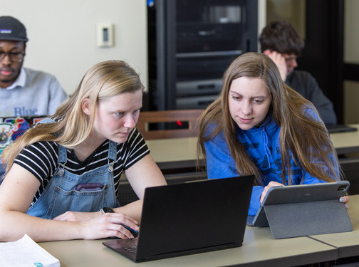 Students in classroom reading from laptops