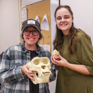 Photograph of UTulsa anthropology students holding large and small skulls 