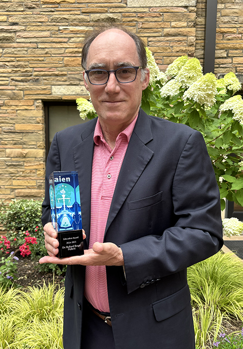 Photograph of University of Tulsa Professor Buford Pollett holding his Association of International Energy Negotiators (AIEN) award