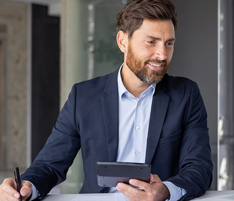 Photograph of a man wearing a suit and holding a tablet device and an ink pen