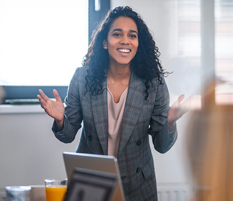 Photograph of a smiling businesswoman in a suit giving a presentation