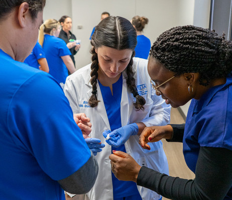 Photograph of three nurses examining something small