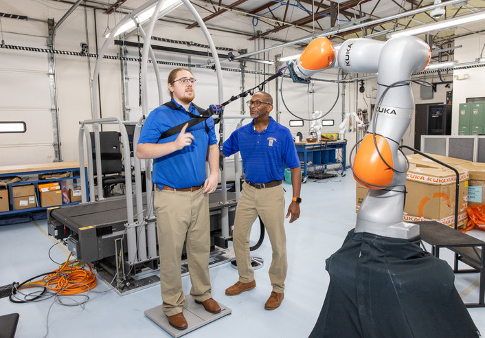 Institute for Robotics: Man using robotic arm for research project with assistance from a colleague.