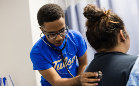 Student using stethoscope to listen to patient's back in integrative healthcare studies program.