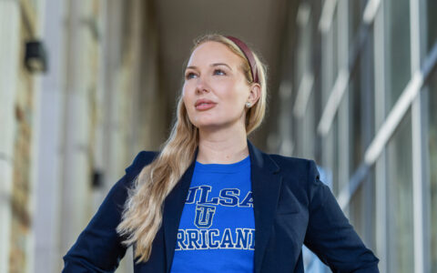 University of Tulsa woman student in Tulsa Hurricane shirt and blazer looking up.