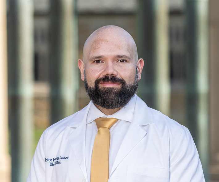 Victor H. Perez, DNP, CRNA, in a white coat and tie. Professional headshot.