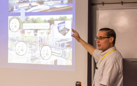 Professor Hawrylak presents digital energy research with a diagram of mobile sensor nodes