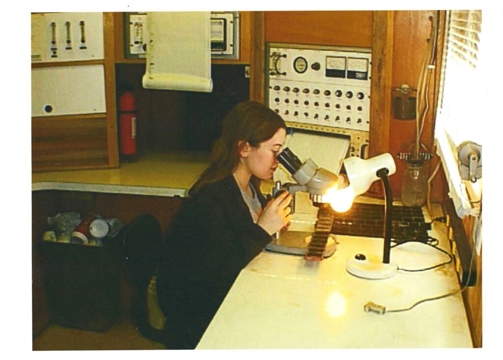 Petroleum engineering professor at microscope, research setting.