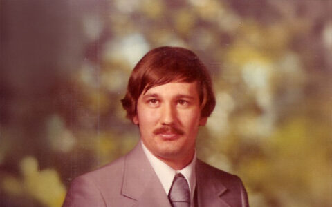 Portrait of a petroleum engineering professor in a grey suit.