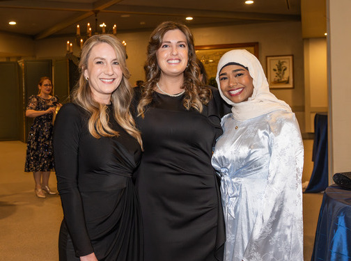 Three women at the Law Alumni Gala, dressed in formal attire, smiling for the camera.