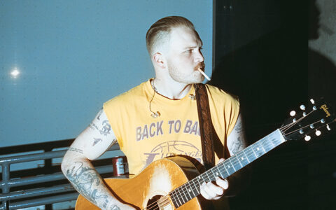 Zach Bryan plays guitar, promoting his tour dates at UTulsa's H.A. Chapman Stadium.