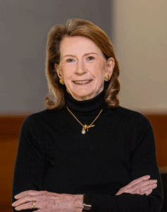 Portrait of a woman in a black turtleneck with arms crossed. 