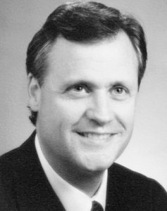 Headshot of a smiling man in a suit, potentially a UTulsa Law alumni. 