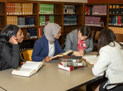 UTulsa law students studying law books around a table in a library.