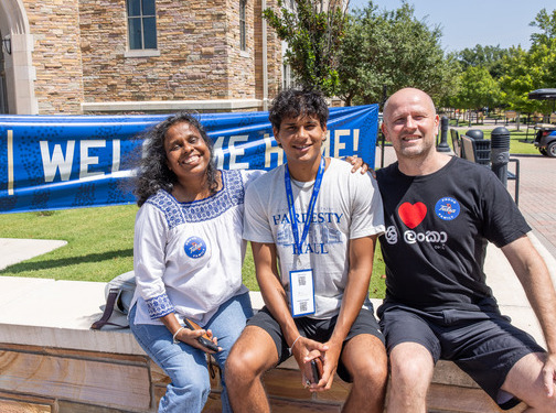 Family at college enrollment event, "Welcome Home!" banner in background.