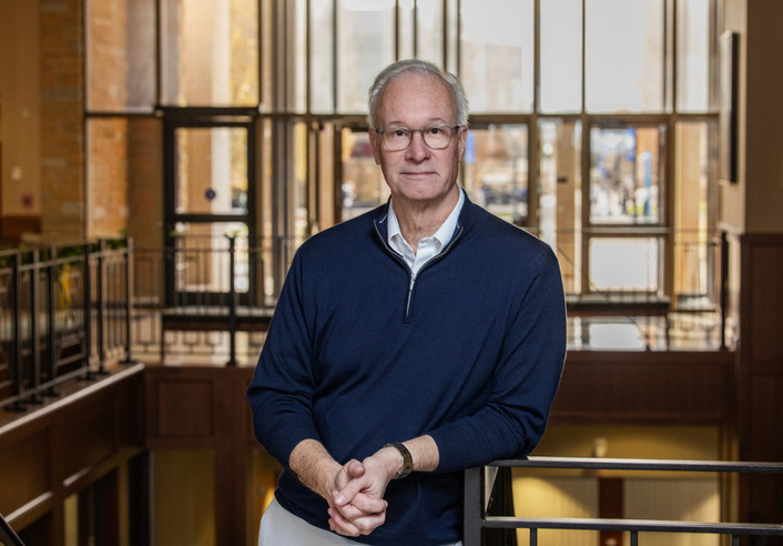 Civil rights litigator in navy pullover at UTulsa Law, leaning on railing.